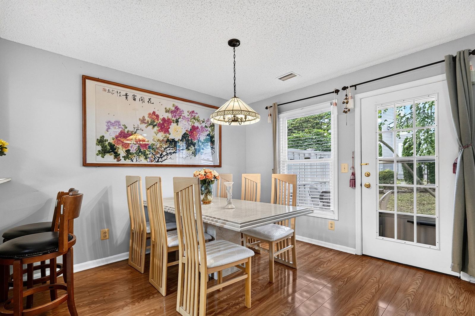 Dining area with a pendant light and a glass-paned door to the fenced backyard