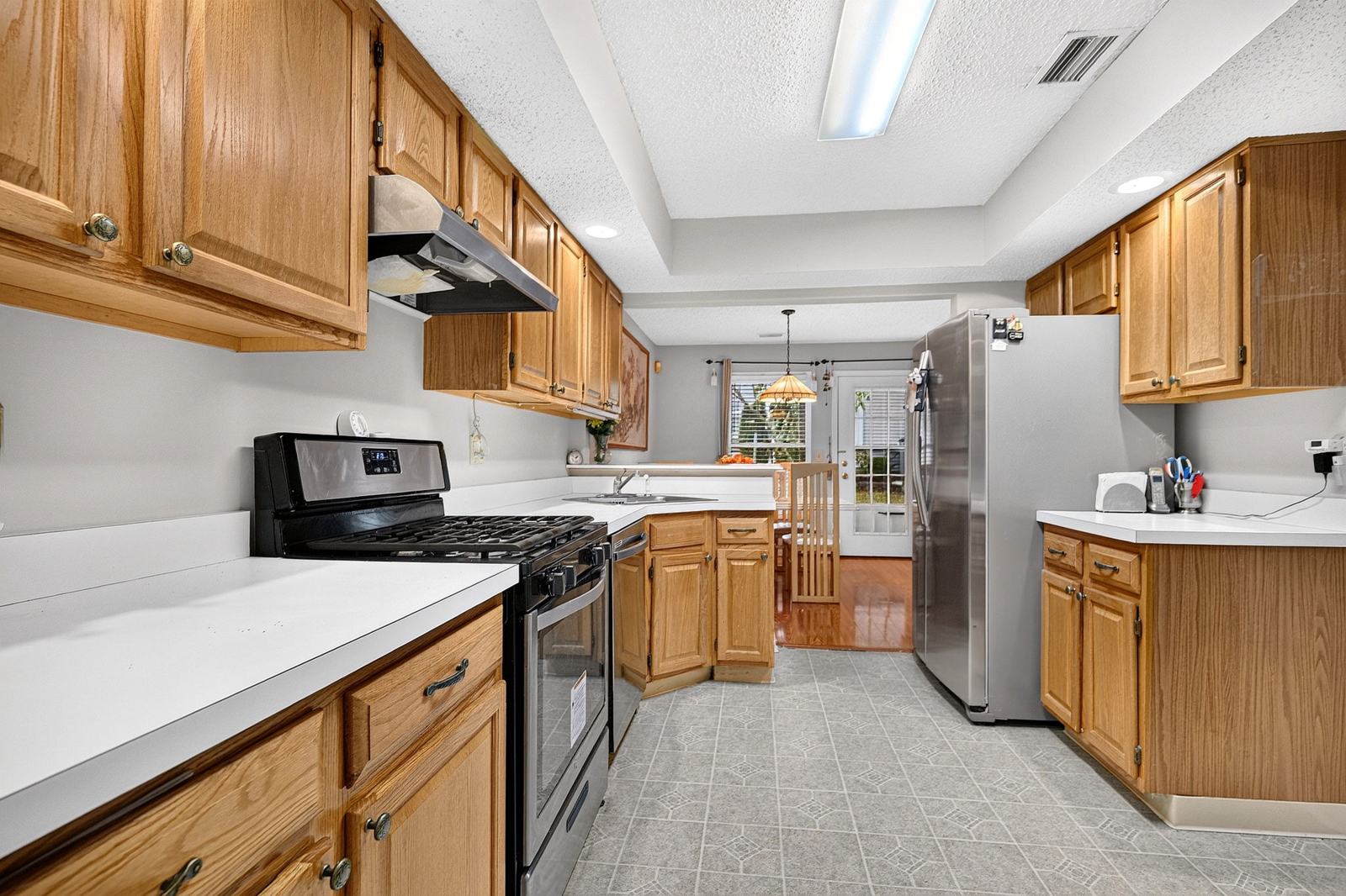 Galley kitchen with side-by-side stainless refrigerator, looking toward the dining area
