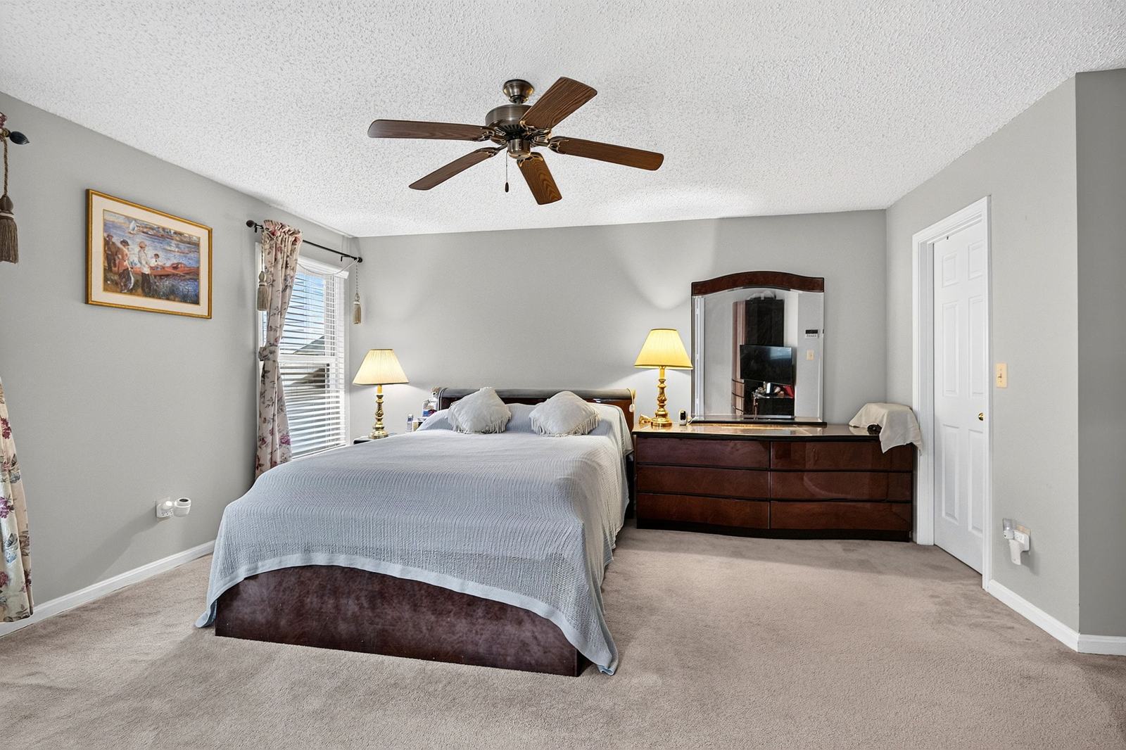Primary suite bedroom with two windows, a ceiling fan and carpet